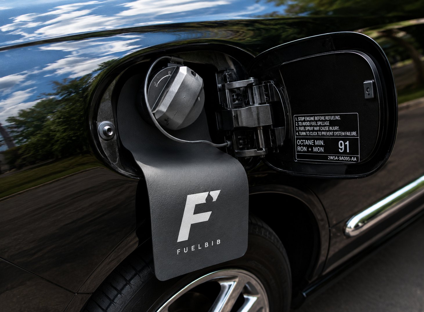A FuelBib hanging on the open fuel door of a black car